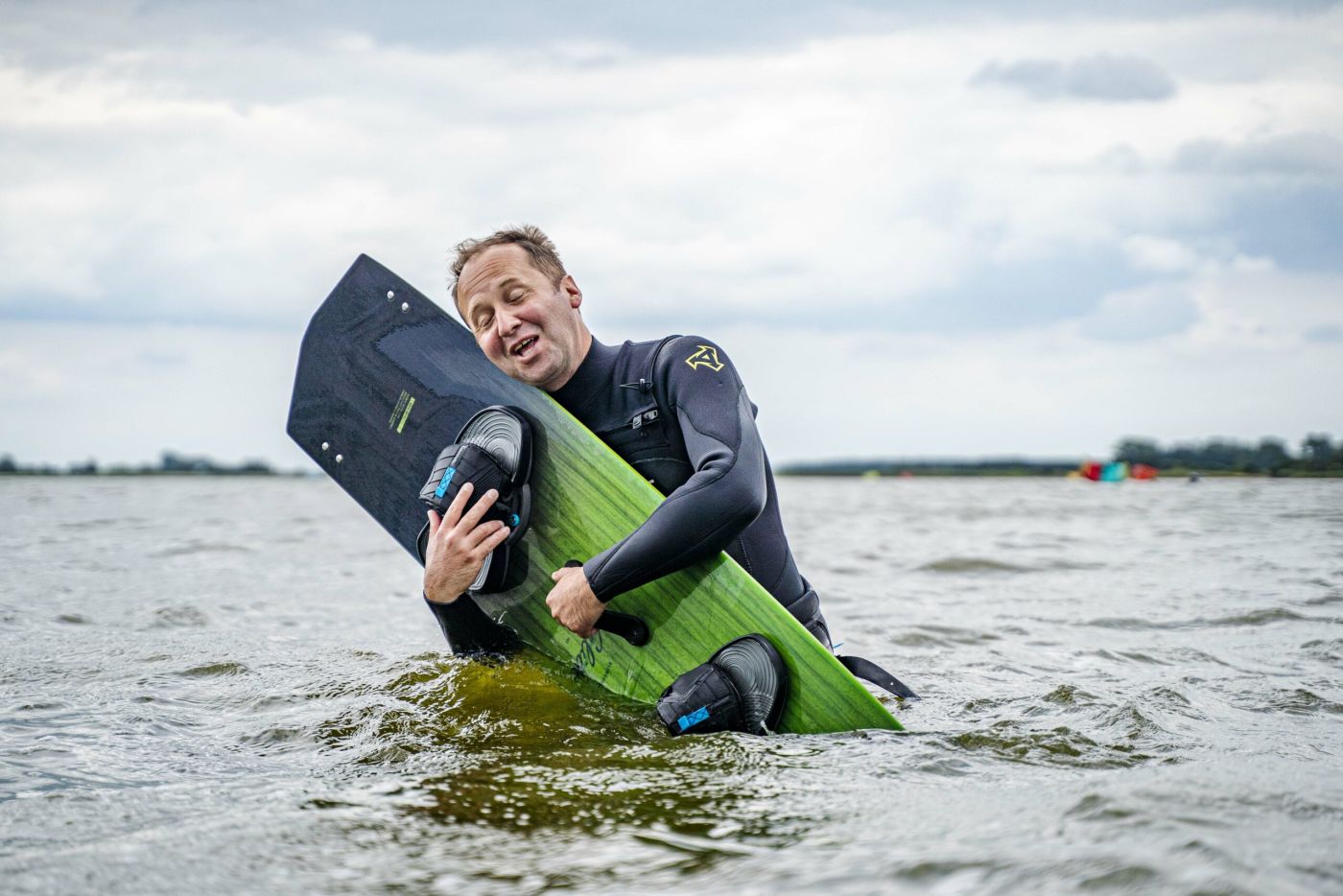 Kiteschüler umarmt sein Board